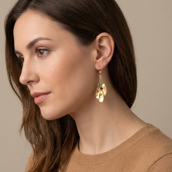 Longues boucles d'oreilles fines modèle Côme de Nune avec trois pointes en métal martelé doré à l'or fin et petites perles de pierres naturelles, portées aux oreilles par une femme brune