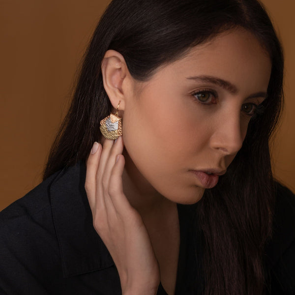 boucle d'oreille aux formes géométriques en cuirs 3 ors,  portée à l'oreille par une femme brune