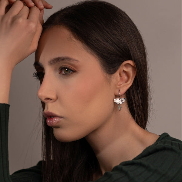 Petites boucles d'oreilles pendantes, de forme demi-lune, en métal martelé argenté et perles de fluorite vert d'eau, portées à l'oreille par une femme brune