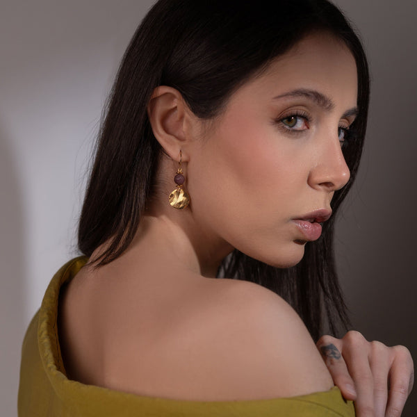 Petites boucles d'oreilles avec sequin rond en métal martelé doré à l'or fin et perles de mokaïte bordeaux, portées à l'oreille par une femme brune