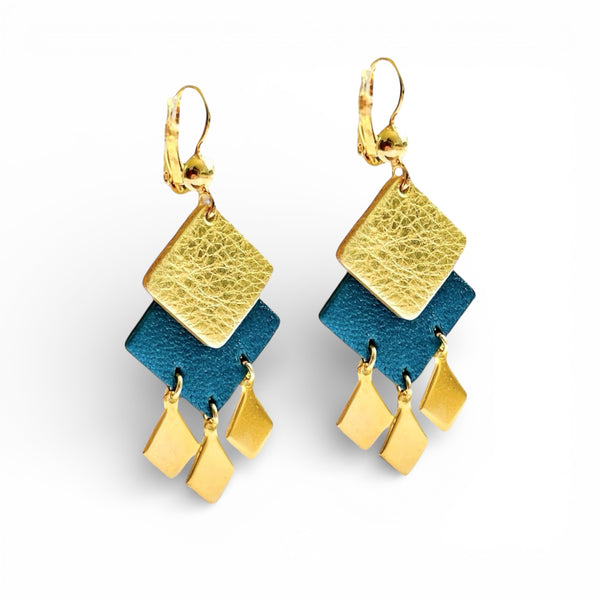 Boucles d'oreilles dorées Diamante en duo de losanges en cuirs doré et bleu nuit métallisé et pendentifs losanges dorés. Forme géométrique, style éthnique sur fond blanc