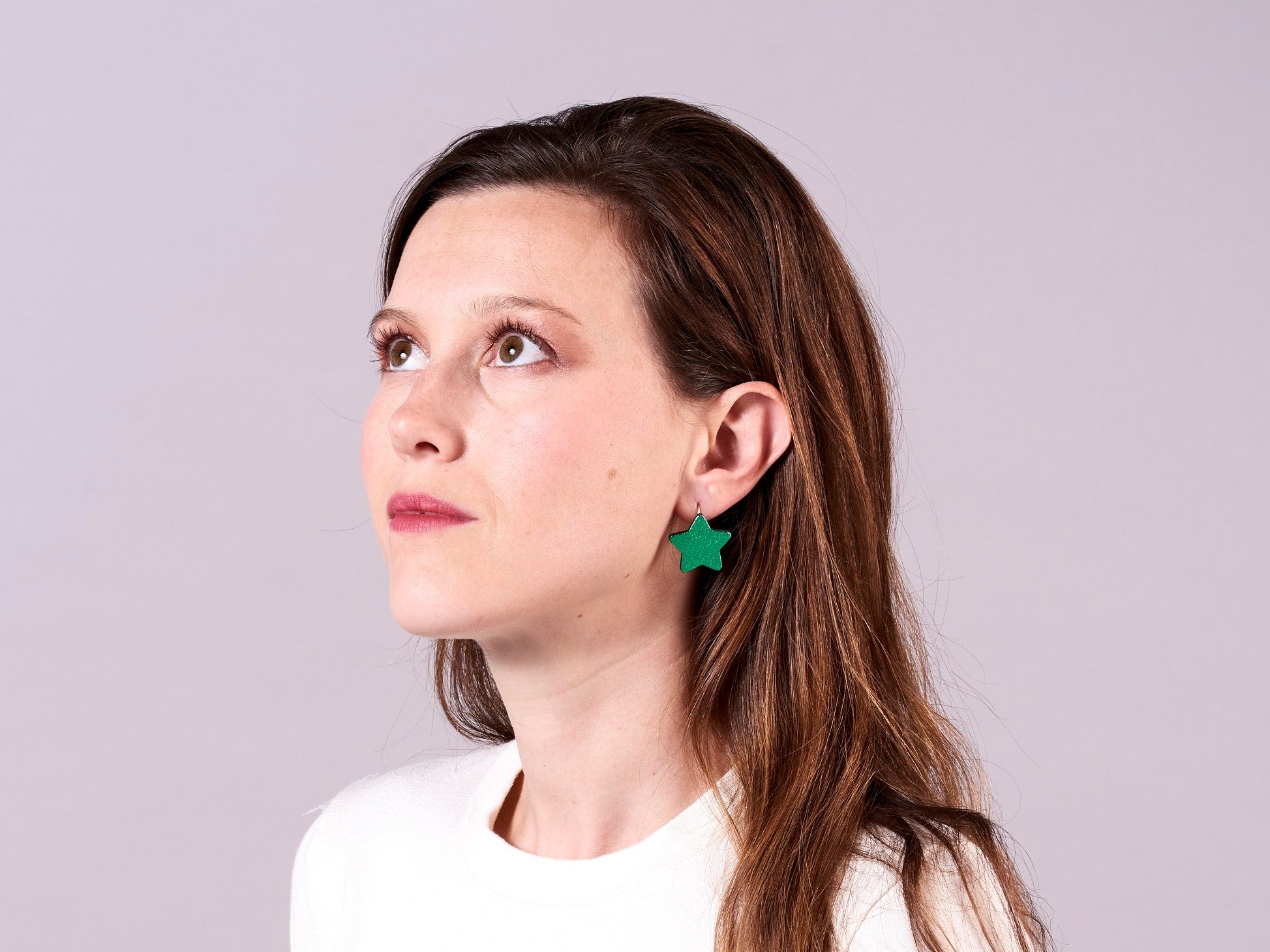 Jeune femme portant les boucles d'oreilles Diva en étoiles de cuir de la marque Nune