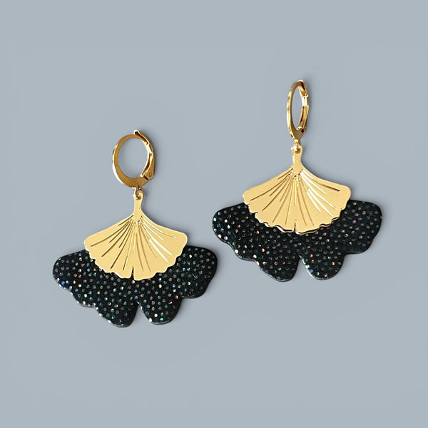 Boucles d'oreilles dorées pendantes en cuir noir à pois holographiques en forme de gingko, sur fond gris