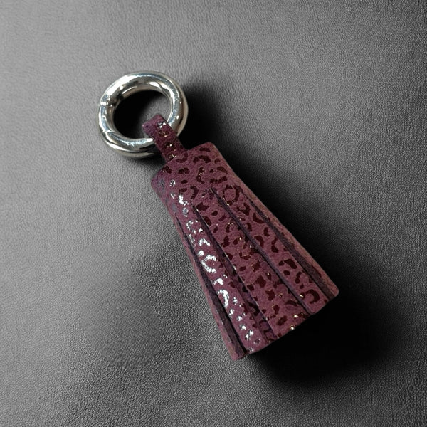 porte-clé argent en cuir prune motif léopard , en forme de pompon, sur fond noir