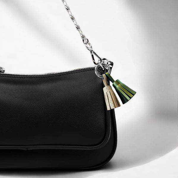 Bijou de sac argenté avec 2 pompons en cuirs beige à pois argent et kaki métallisé, accroché sur un sac à main noir