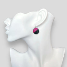 Charger l&#39;image dans la galerie, Boucles d&#39;oreilles rondes argentées bicolores en cuirs fushia métallisé et noir grainé, portées à l&#39;oreille sur un buste blanc
