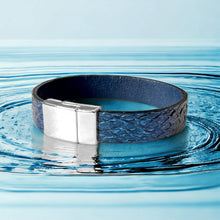 Charger l&#39;image dans la galerie, bracelet en cuir marin bleu saphir métallisé avec fermoir argent aimanté, sur une eau bleue
