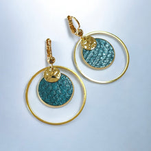 Charger l&#39;image dans la galerie, Paire de boucles d&#39;oreilles dorées rondes pendantes de style créoles avec sequin en cuir marin bleu paon métallisé, vue de côté, sur fond gris
