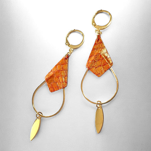 Boucles d'oreilles Gali de Nune, dorées à l'or fin avec triangle de cuir marin, cuir de poisson saumon orangé or, de forme grande goutte, sur fond cuir gris 