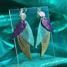 Charger l&#39;image dans la galerie, Boucles d&#39;oreilles argentées Nune en forme de plumes, modèle Ara en cuirs violet brillant façon serpent, turquoise métallisé et kaki métallisé sur fond cuir turquoise métallisé
