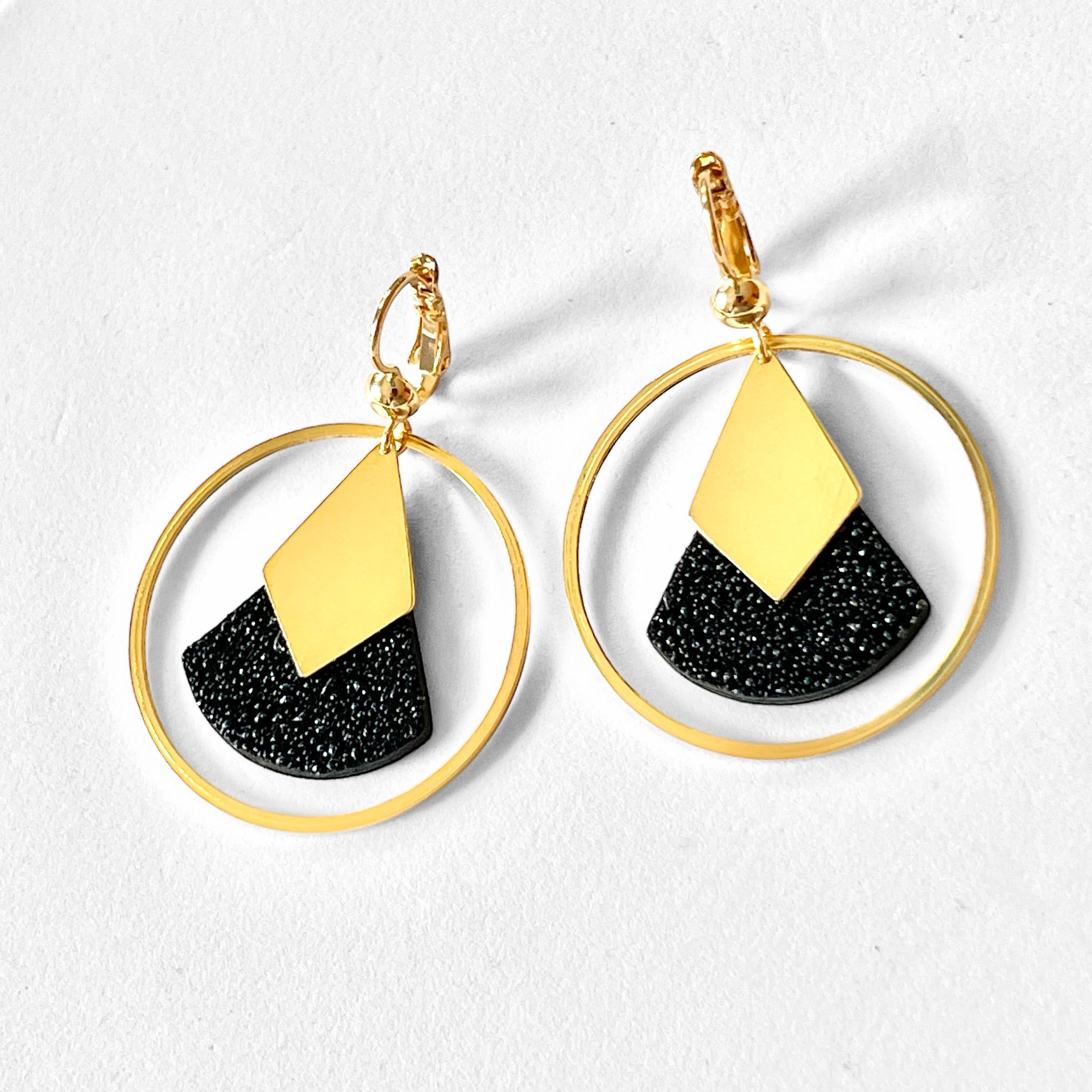 Boucles d'oreilles dorées à l'or fin Nune modèle Scala Créoles en cuir noir grainé pailleté sur fond blanc