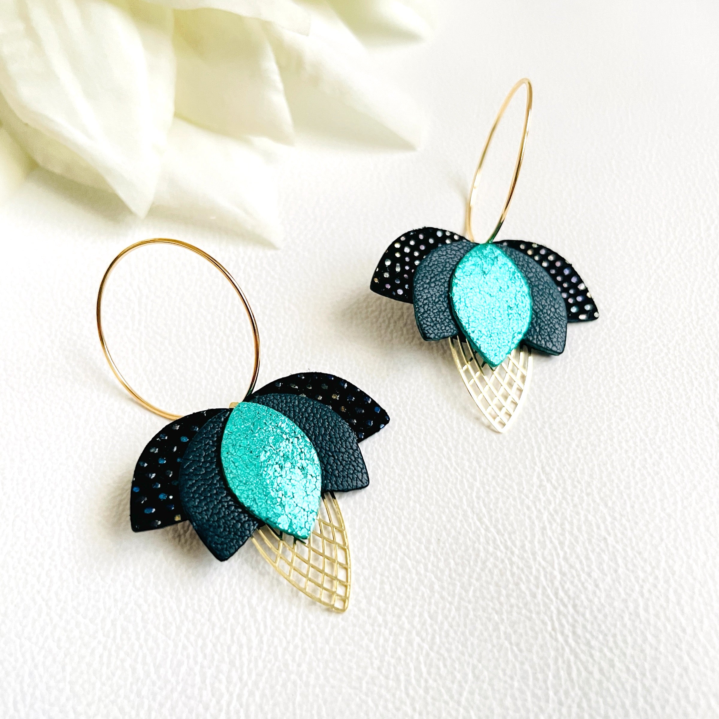 Créoles dorées en forme de fleurs de Lotus en cuirs noir grainé irisé, vert sombre et vert émeraude brillant intense sur fond blanc