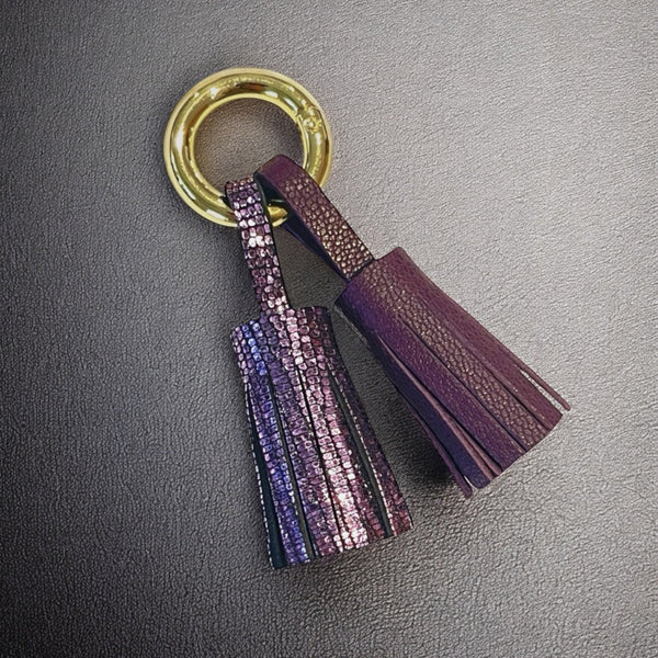 Bijou de sac doré avec 2 pompons en cuirs Violet brillant façon serpent et violine satinée, sur fond noir