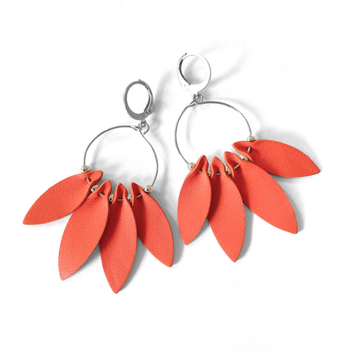 Grandes et longues boucles d'oreilles argentées en forme de couronne de plumes, en cuir orange carotte, sur fond blanc