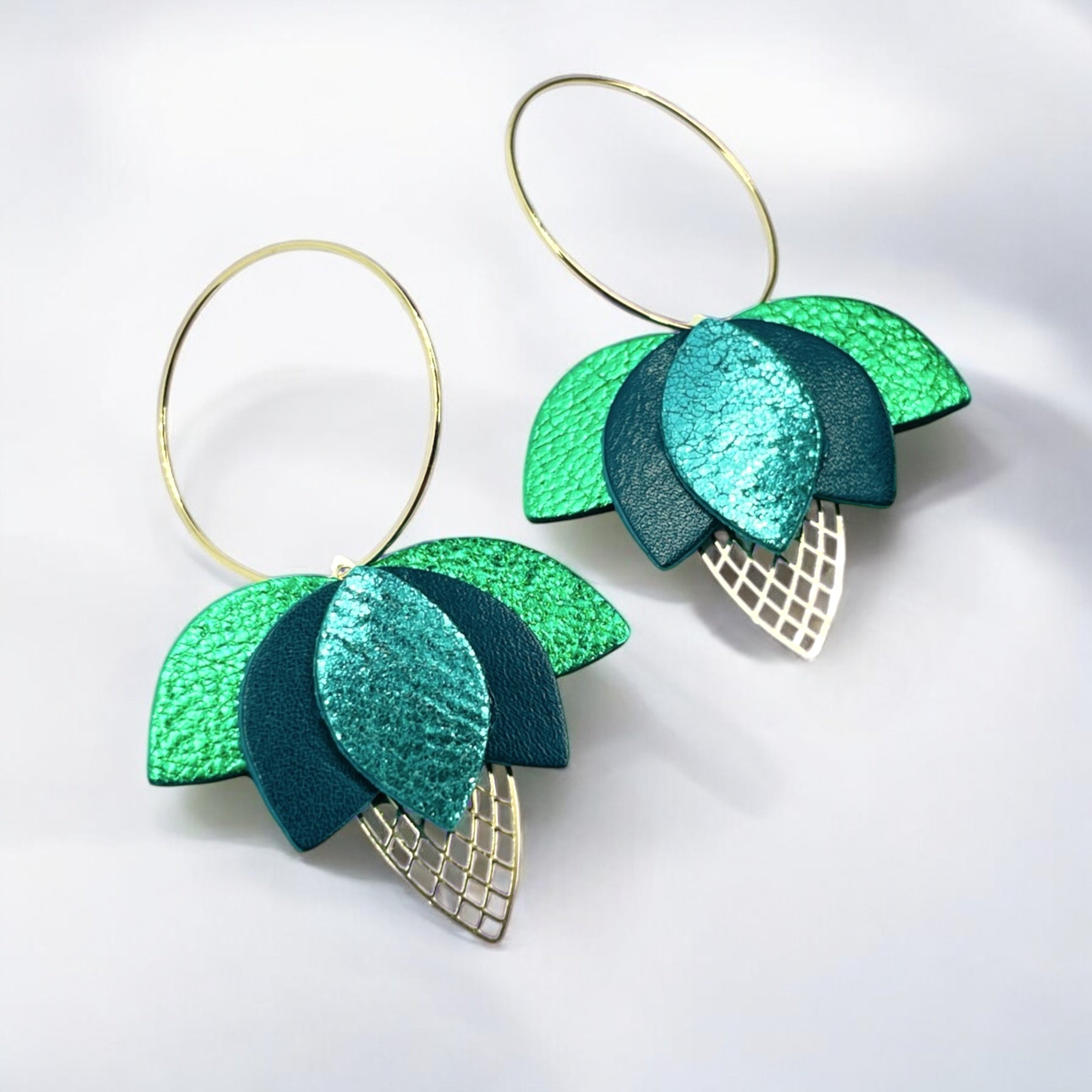 Créoles dorées en forme de fleurs de Lotus en cuirs vert émeraude, vert canard et vert métallisé sur fond blanc