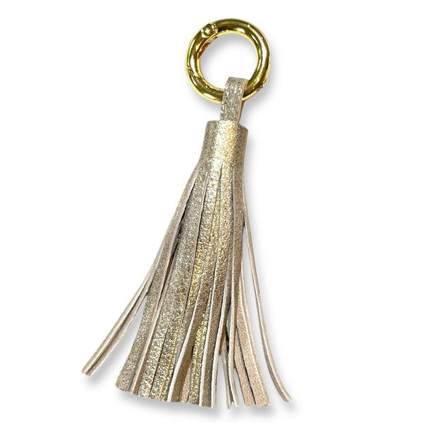 Bijou de sac doré portant un grand pompon en cuir doré vintage , sur fond blanc