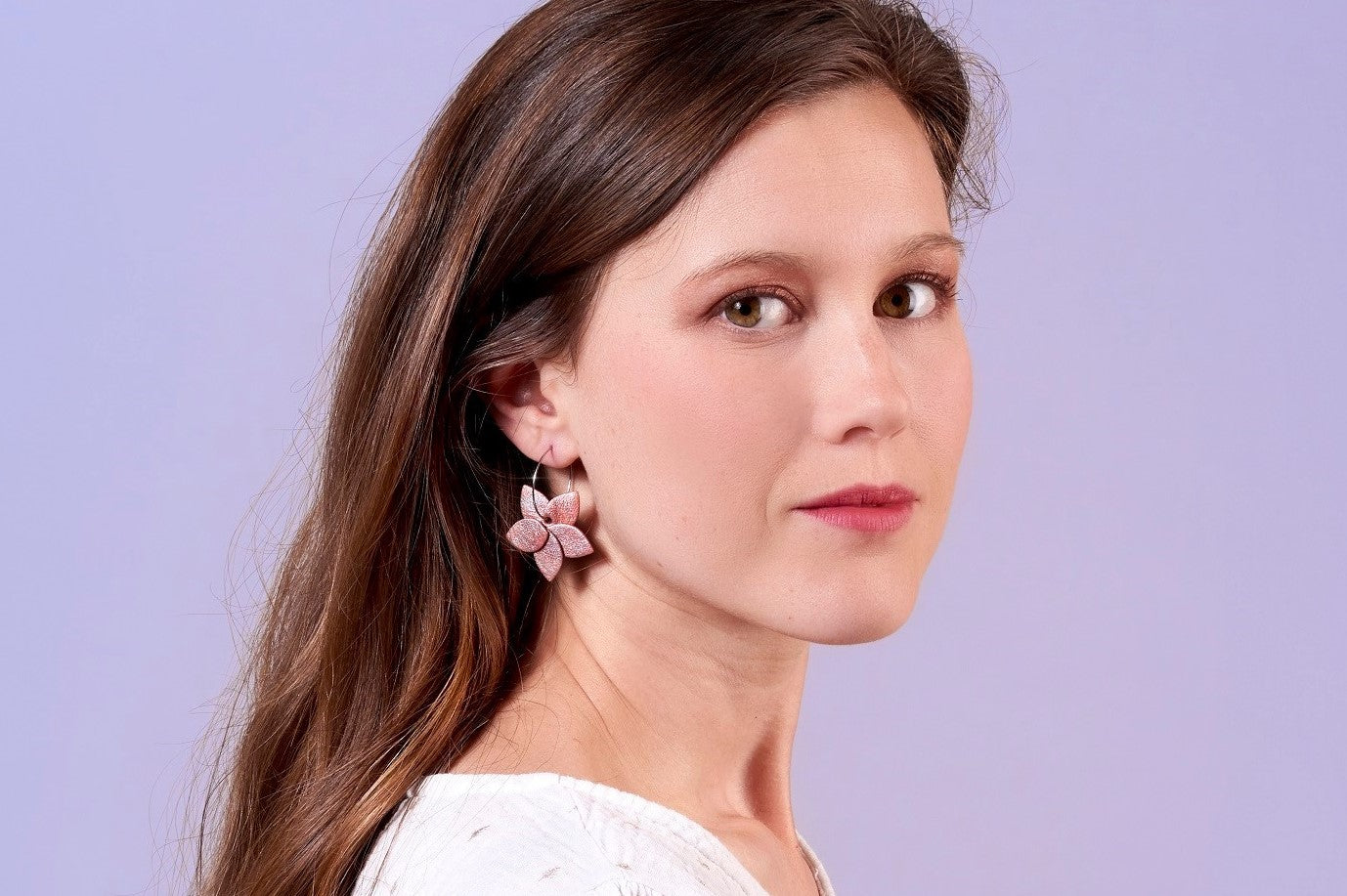 Jeune femme portant les boucles d'oreilles Jasmin argenté en pétales de cuir de la marque Nune