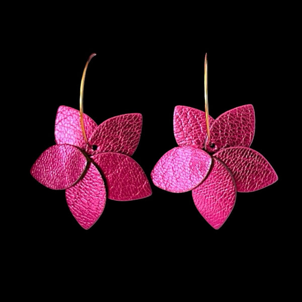 Petites boucles d'oreilles en forme de fleurs en cuir fushia métallisé montées sur créoles dorées, sur fond noir