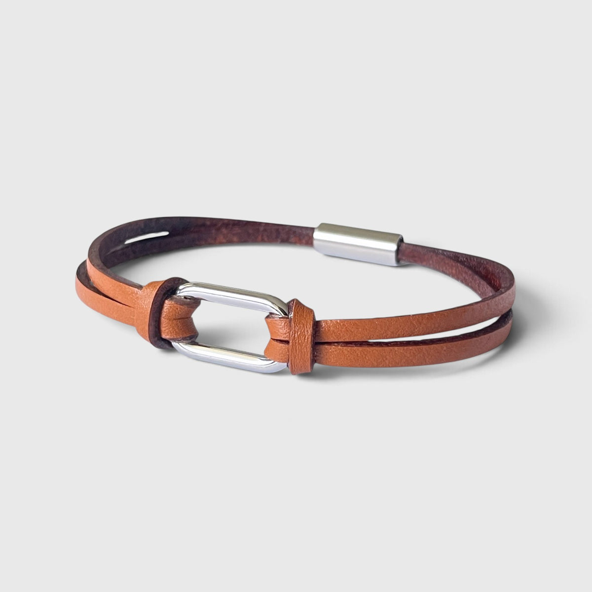 Bracelet homme à boucle argentée en fins liens de cuir fauve grainé avec fermoir aimanté argenté, vu à plat