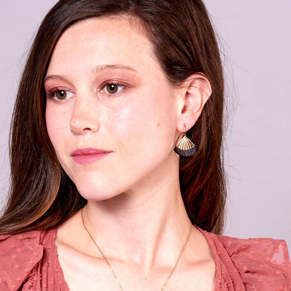 Jeune femme portant les Boucles d'oreilles dorées Nune modèle Alya avec sequin éventail et pièces de cuir noir grainé irisé