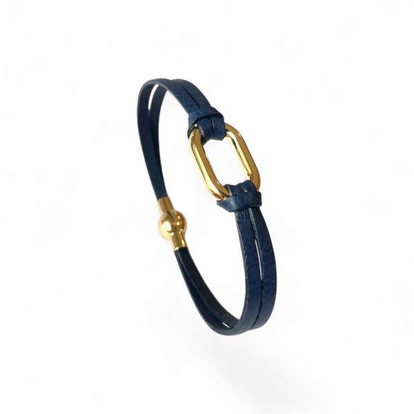 Bracelet à boucle dorée en fins liens de cuir bleu marine, avec fermoir aimanté doré, présenté debout, sur fond blanc