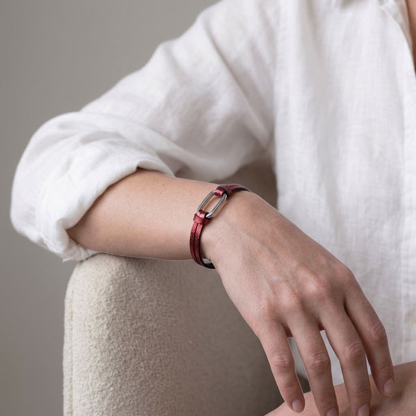 Bracelet femme à boucle argentée en fins liens de cuir grenat métallisé, avec fermoir aimanté argenté, porté