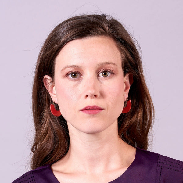 Jeune femme portant les Boucles créoles Nune modèle Mezzaluna dorées en forme de demi-lunes en cuir recyclé coquelicot nacré