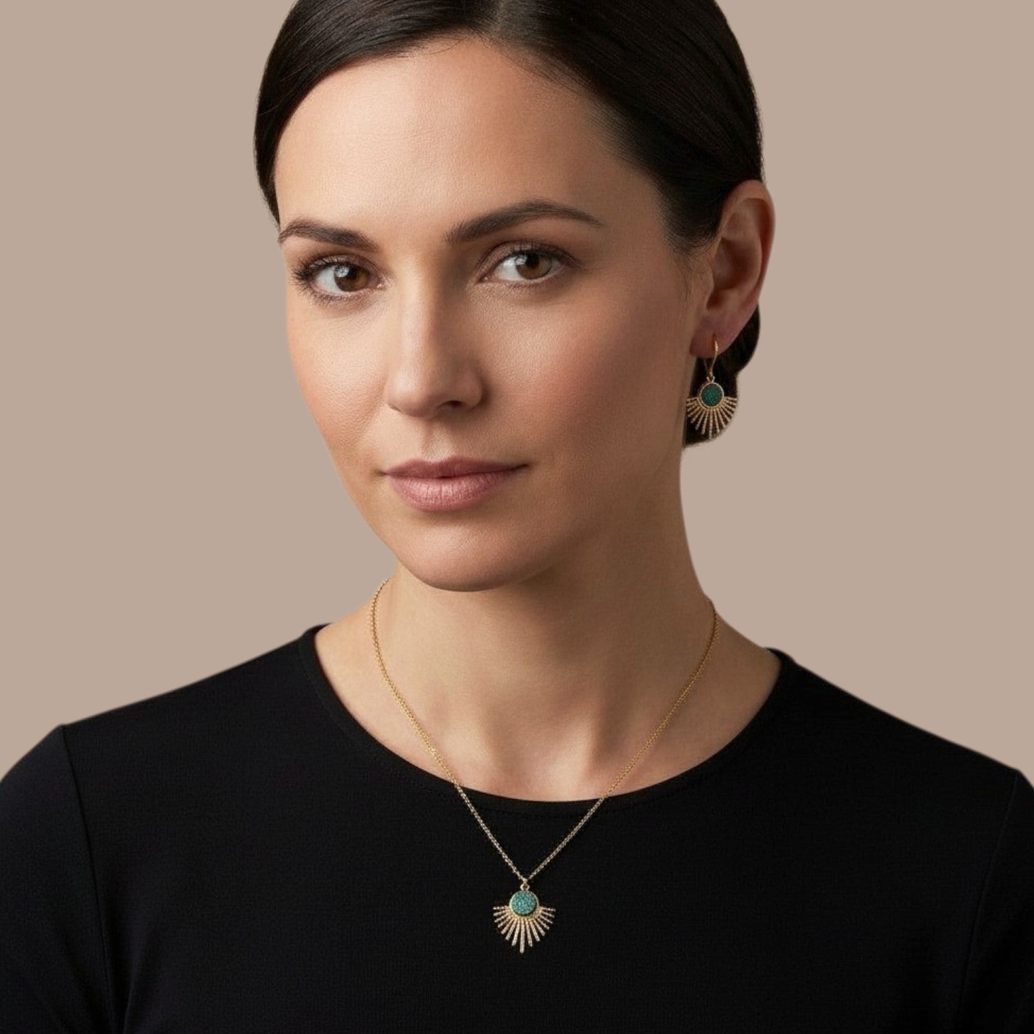 Collier doré fin avec pendentif en forme de petit soleil, avec cabochon de cuir coloré revalorisé bleu paon pailleté, porté par une femme brune, qui porte aussi aux oreilles les boucles d'oreilles dorées Miria assorties au collier