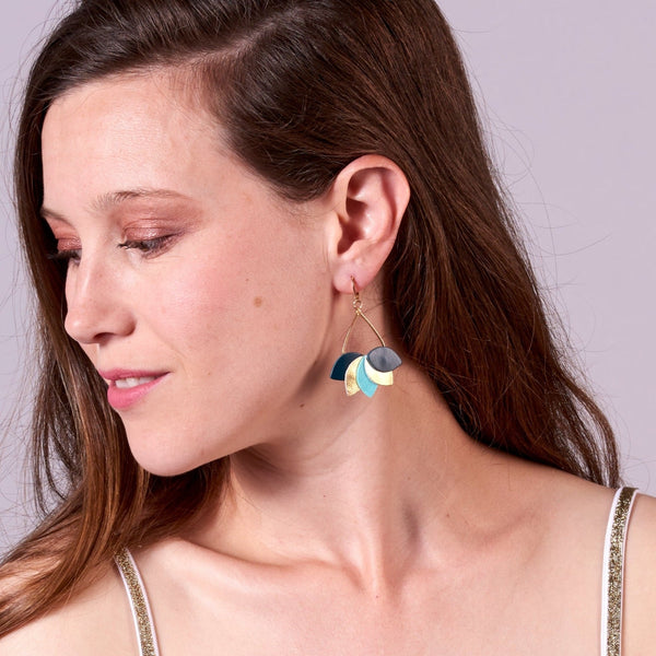 Jeune femme vue de profil portant les Boucles d'oreilles Nune modèle Aponi dorées à l'or fin avec pétales de cuir vert canard, doré brillant et vert menthe satiné, en forme de couronne de pétales