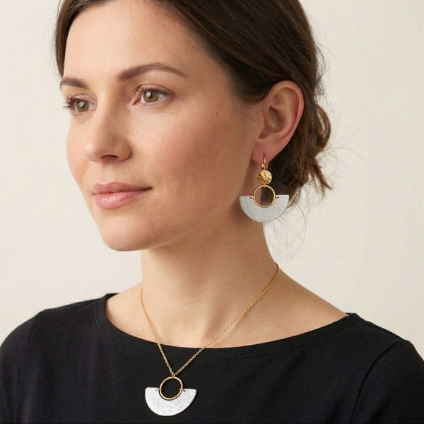 Femme portant la parure Artea , collier et boucles d'oreilles dorés avec demi-lune en liège argent.