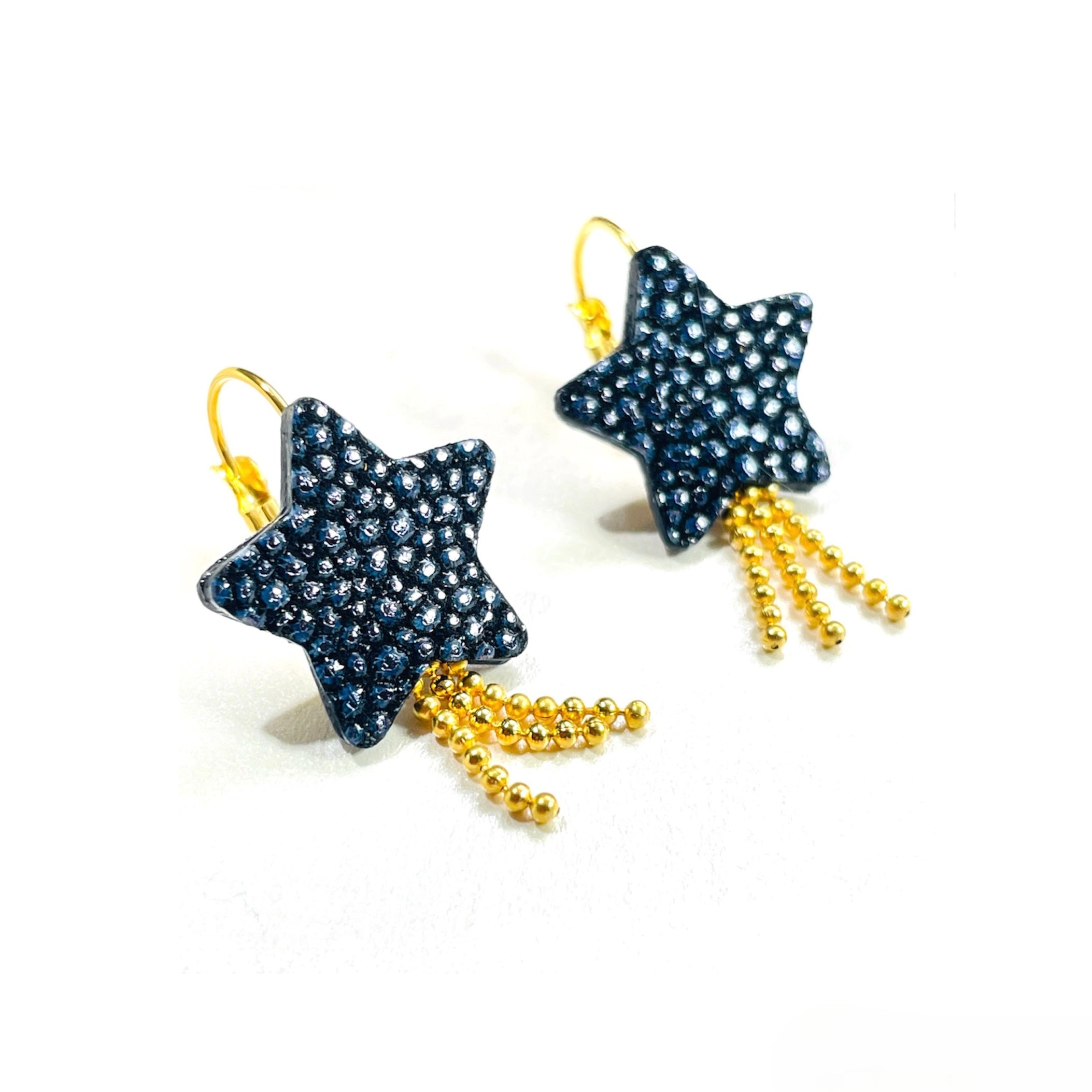 boucles d'oreilles dorées Nune modèle Stella en forme d'étoiles, en cuir bleu nuit grainé irisé, sur fond blanc