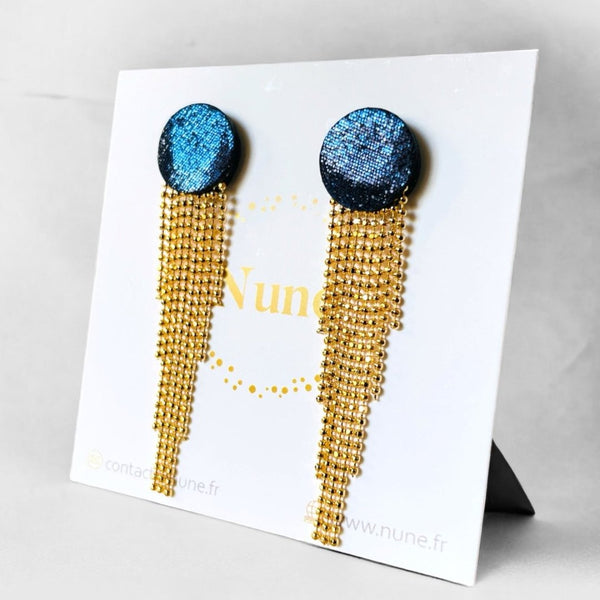 Puces d'oreilles rondes et élégantes en cuir bleu marine pailleté avec leur cascade de fines chaînettes dorées, sur fond blanc