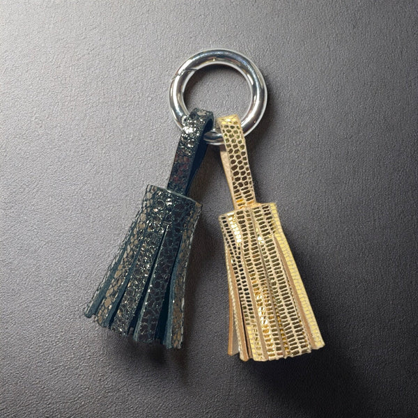 Bijou de sac argenté avec 2 pompons en cuirs gris craquelé métallisé et doré façon serpent, sur fond noir