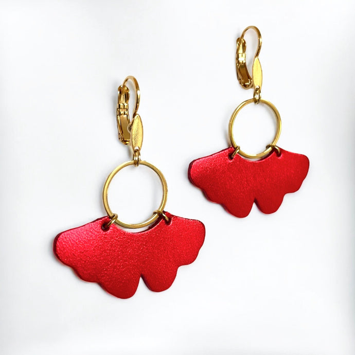 boucles d'oreilles dorées en forme de feuille de gingko en cuir rouge métallisé, sur fond blanc