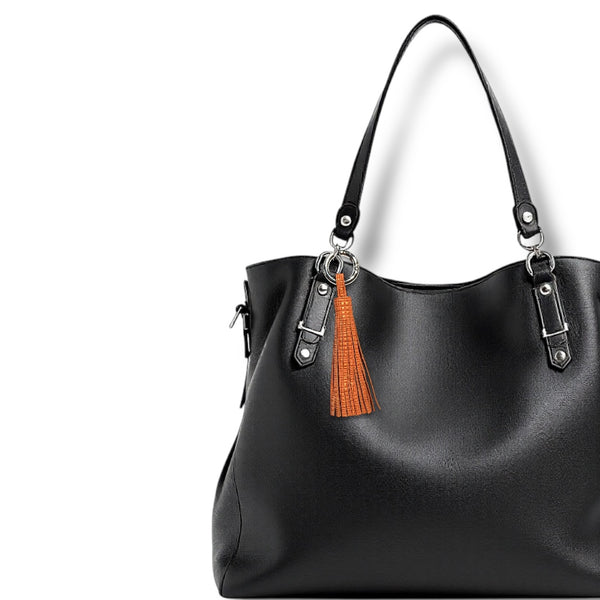 Bijoux de sac argenté grand pompon en cuir orangé or mat, sur un sac en cuir noir