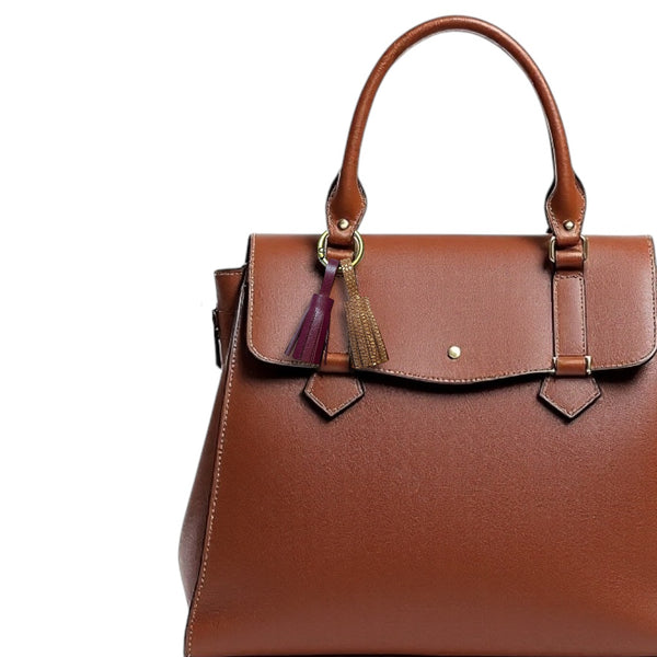 Bijou de sac bronze avec 2 pompons en cuirs pourpre et fauve or façon serpent, sur un sac en cuir brun