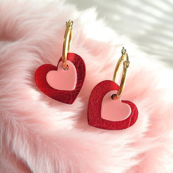 Boucles créoles dorées avec pendentifs en forme de cœurs rouge métallisé et rose vernis, sur fourrure rose pastel