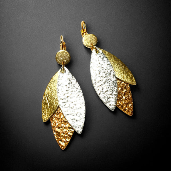 Boucles d'oreilles modèle Ombline de la marque Nune, avec dormeuses dorées et pétales de cuirs trois Ors sur fond noir