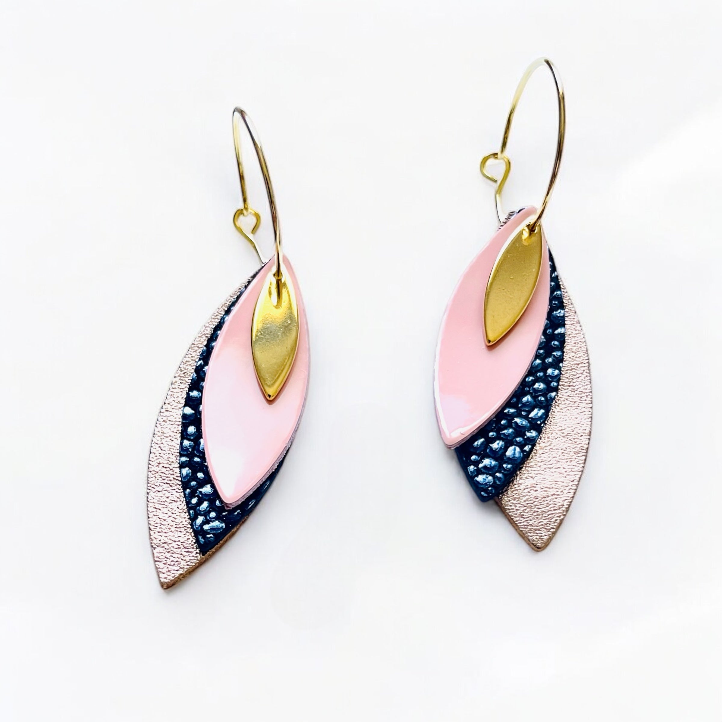 Boucles d'oreilles créoles dorées Nune modèle Piume en cuirs rose pastel vernis, bleu nuit grainé irisé et cannelle dorée satinée sur fond blanc