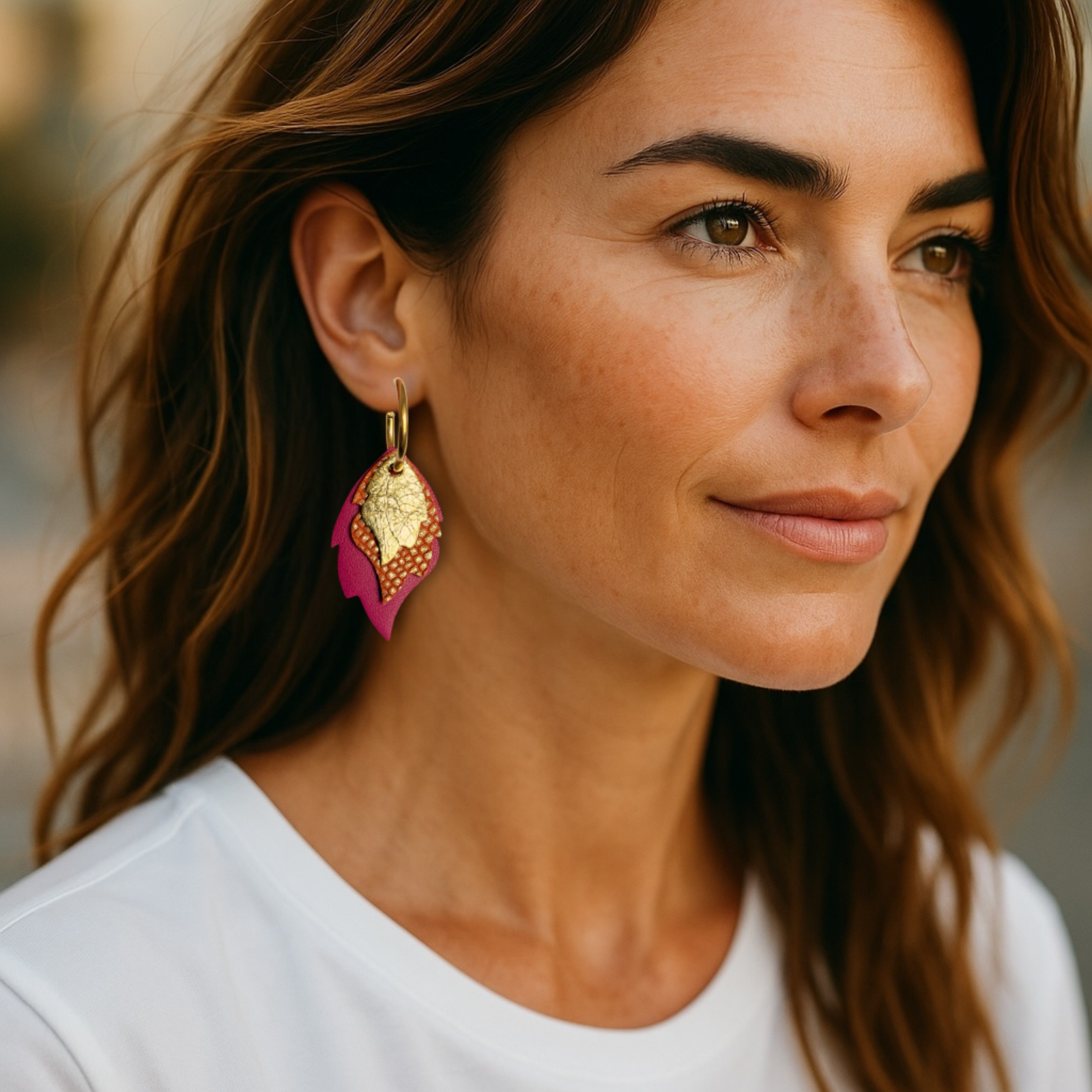 Créoles dorées avec 3 pendentifs modulables en forme de flammes en cuirs doré brillant, orangé or façon serpent et fushia, portées à l'oreille par une femme brune