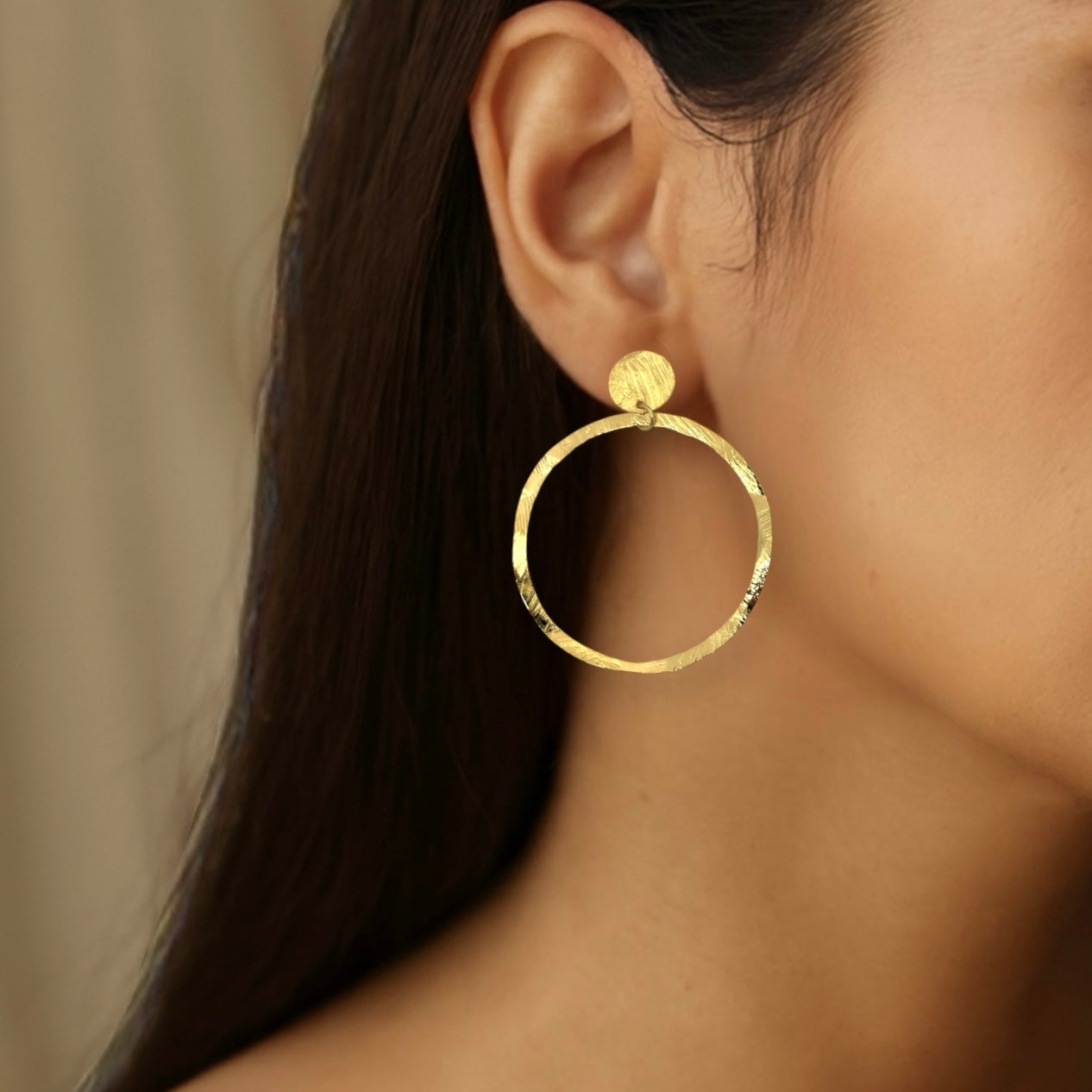 Grandes boucles d'oreilles créoles dorées en métal martelé, montées sur puces rondes, portées aux oreilles