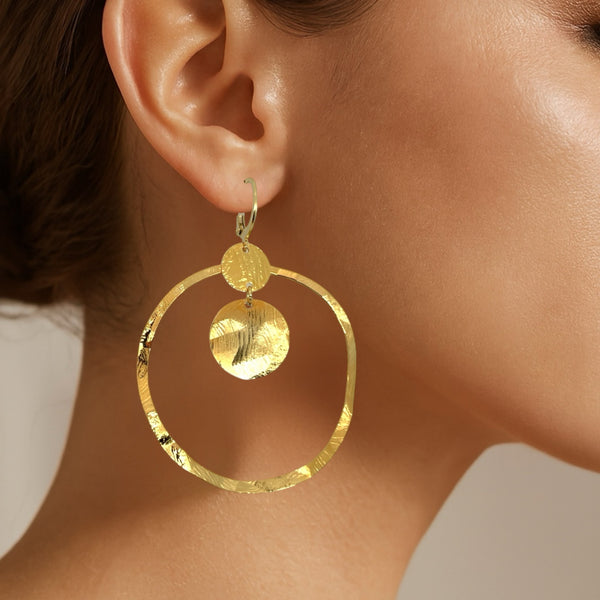 Grandes boucles d'oreilles créoles dorées avec sequins en métal martelé, avec attaches-dormeuses, portées aux oreilles