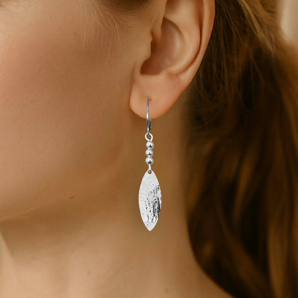 Boucles d'oreilles argentées fines pendantes longues en pointes, portées aux oreilles 