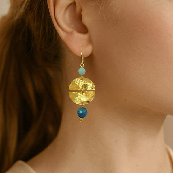 Boucles d'oreilles pendantes de forme ronde avec 2 demi-lunes, en métal martelé doré à l'or fin et perles d'amazonite et d'apatite bleue, portées à l'oreille
