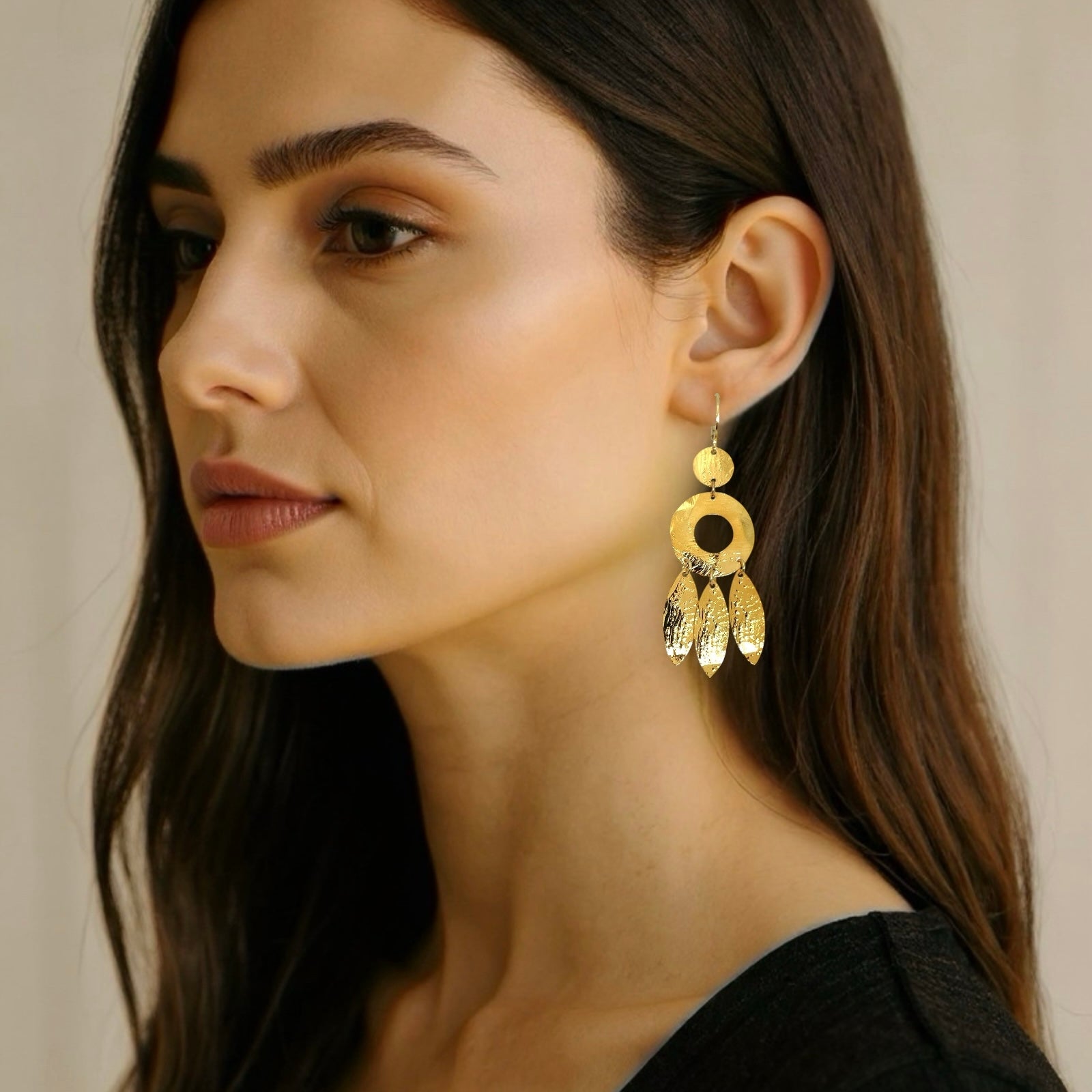 Longues boucles d'oreilles dorées à l'or fin en métal martelé, de style ethnique bohème chic, avec leurs pampilles en forme de plumes, portées aux oreilles