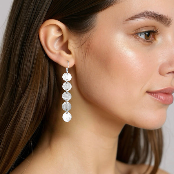 Fines longues boucles d'oreilles argentées pendantes en chapelet de 5 petits sequins ronds, portées aux oreilles