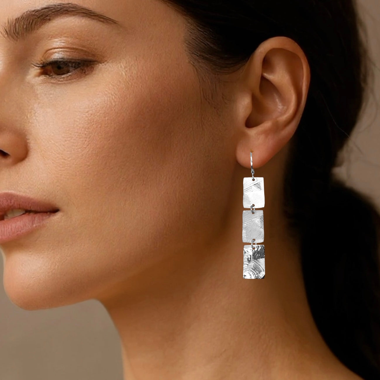Boucles d'oreilles pendantes en chapelet de 3 rectangles en métal martelé argenté, portées aux oreilles