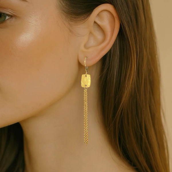 Fines boucles d'oreilles pendantes en métal martelé doré à l'or fin avec pendant rectangulaire et chainette, portées aux oreilles