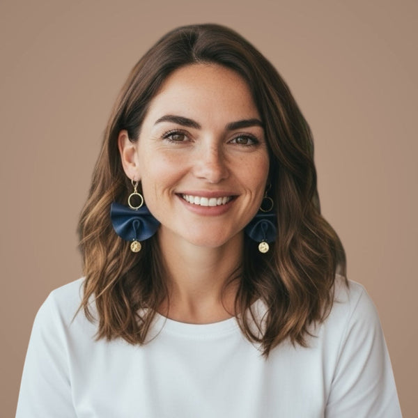 Grandes boucles d'oreilles dorées en éventails de cuir plissé recyclé bleu marine satiné, portées aux oreilles