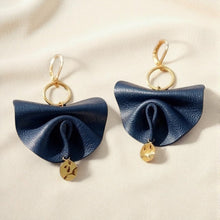 Charger l&#39;image dans la galerie, Grandes boucles d&#39;oreilles dorées en éventails de cuir plissé recyclé bleu marine satiné, sur fond beige
